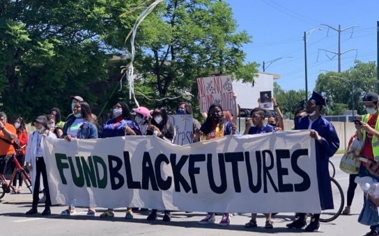 crowd holding a sign that says fund black futures