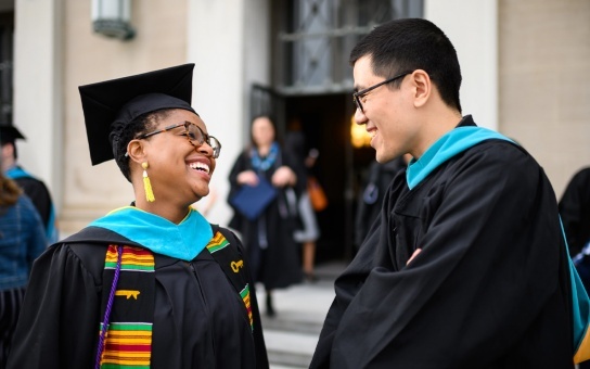 students smiling together in graduation robes