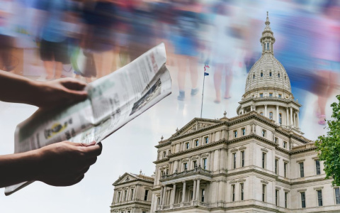 hands holding a newspaper, michigan capitol building 